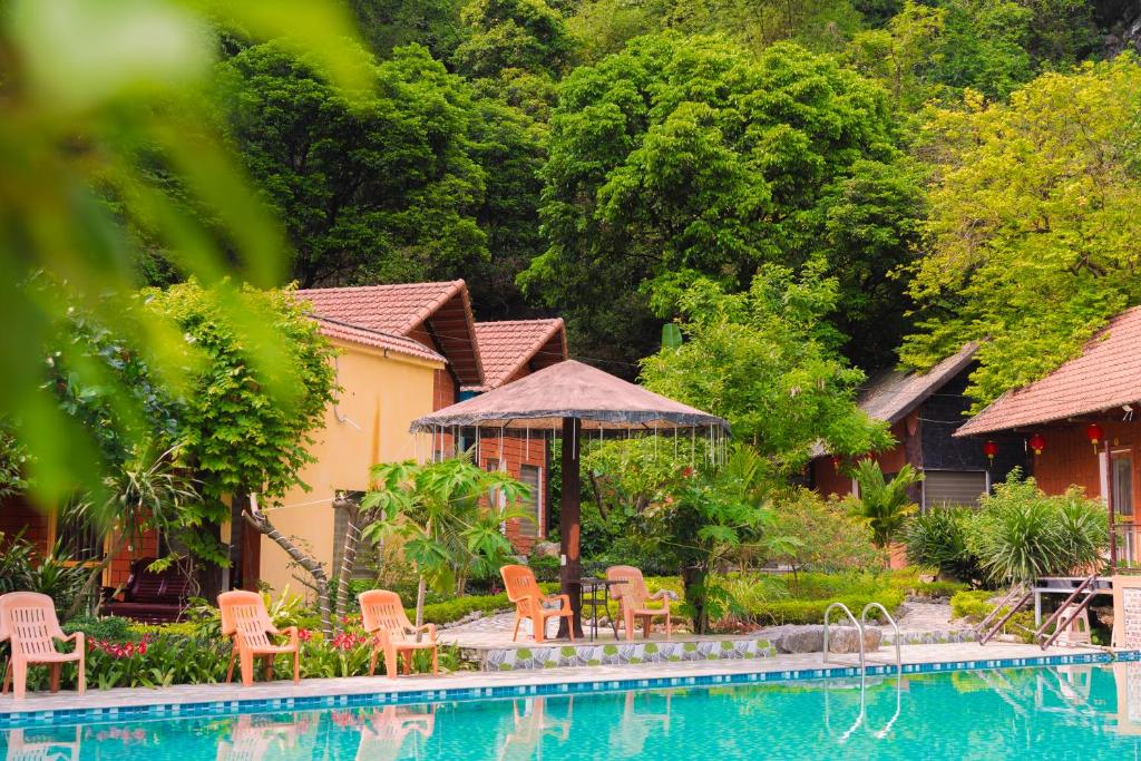 a resort with a swimming pool and chairs and trees at Trang An Hometown Homestay in Ninh Binh