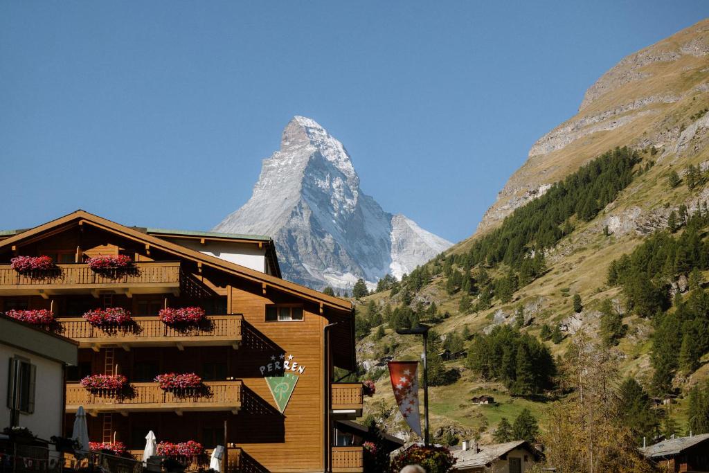 a building with flowers in front of a mountain at Alpine Hotel Perren in Zermatt