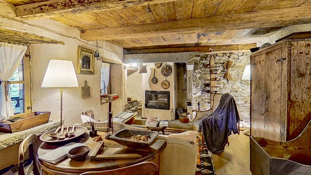 - un salon avec une table et un mur en pierre dans l'établissement Ca' Scocc, antica casa di montagna in Valsesia, à Mollia