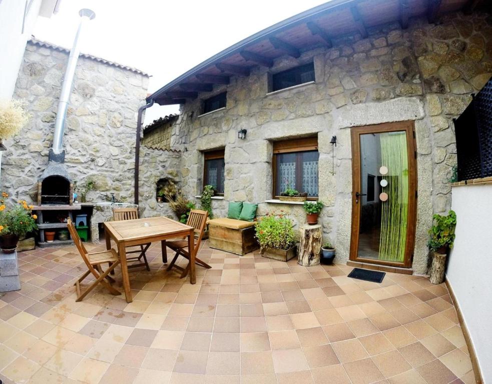 a patio with a table and chairs in front of a stone building at Casa La Charca 