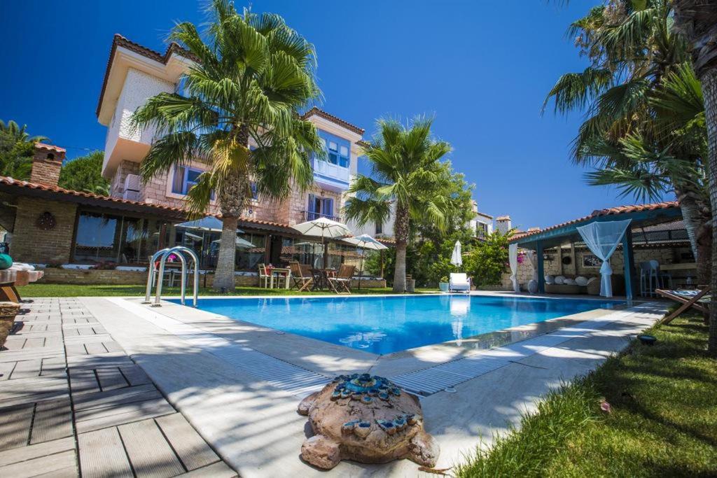 a swimming pool in front of a house with palm trees at Tash Mekan Alaçatı in Alaçatı