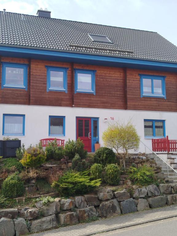 a house with a red door and a stone wall at Holzhausidylle am Steimel in Neunkirchen