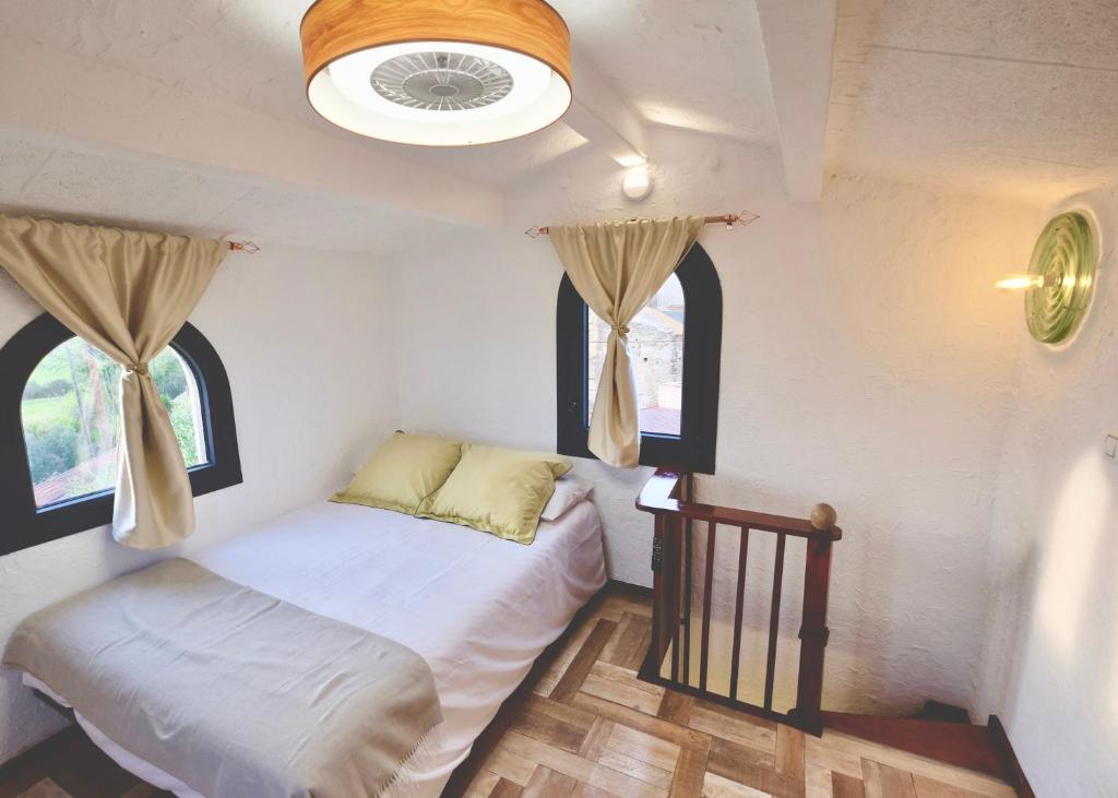a small bedroom with a bed and two windows at Torre Costa Brava in Garrigás