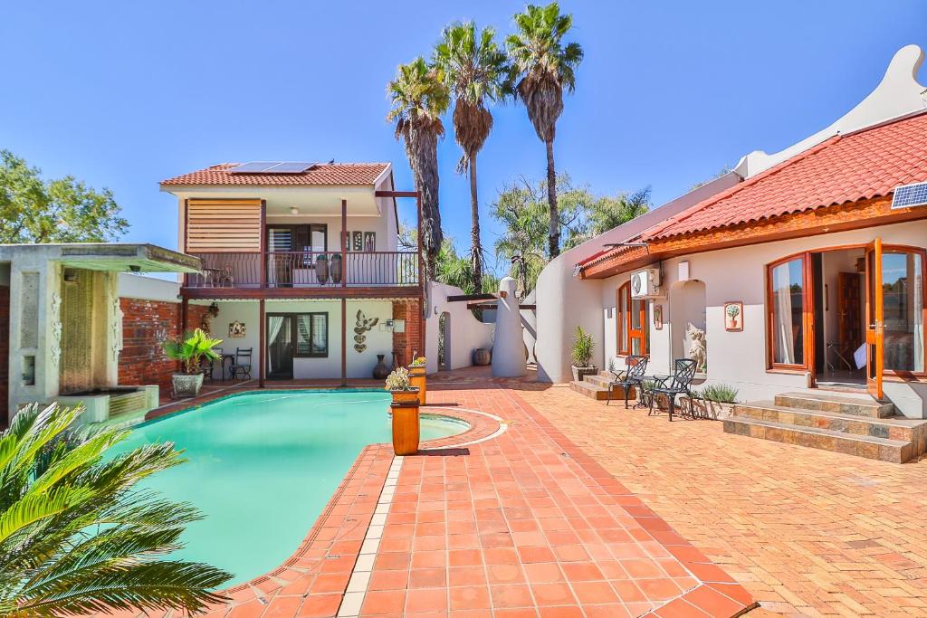 a house with a swimming pool and a fire hydrant at Cascade Villa Guesthouse in Secunda