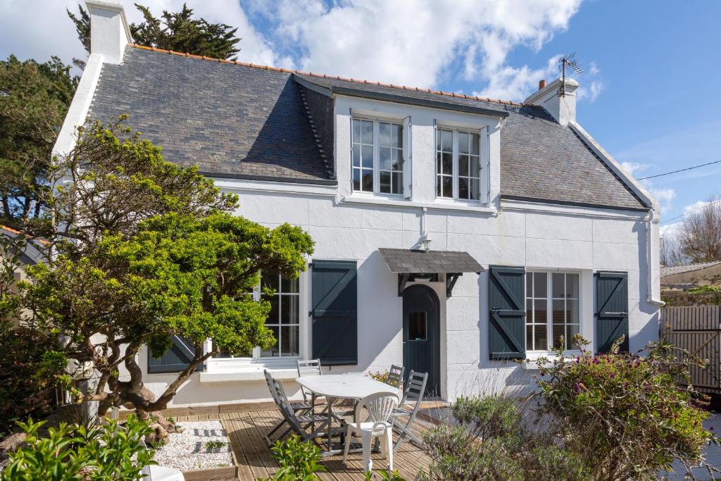 a white house with a table and chairs at Maison Gavres - Bord de mer in Gâvres