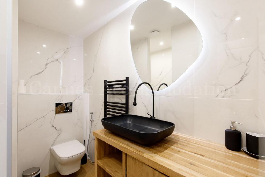 une salle de bain avec un lavabo noir et un miroir dans l'établissement Kiss, à Cannes
