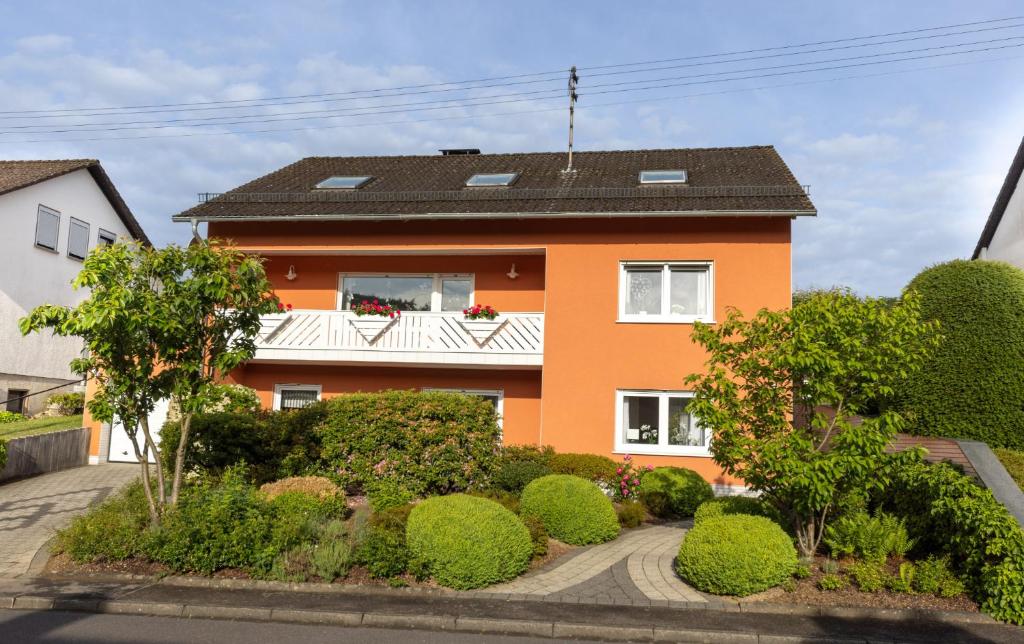 an orange house with a balcony and bushes at Ferienwohnung Hoffmann in Netphen