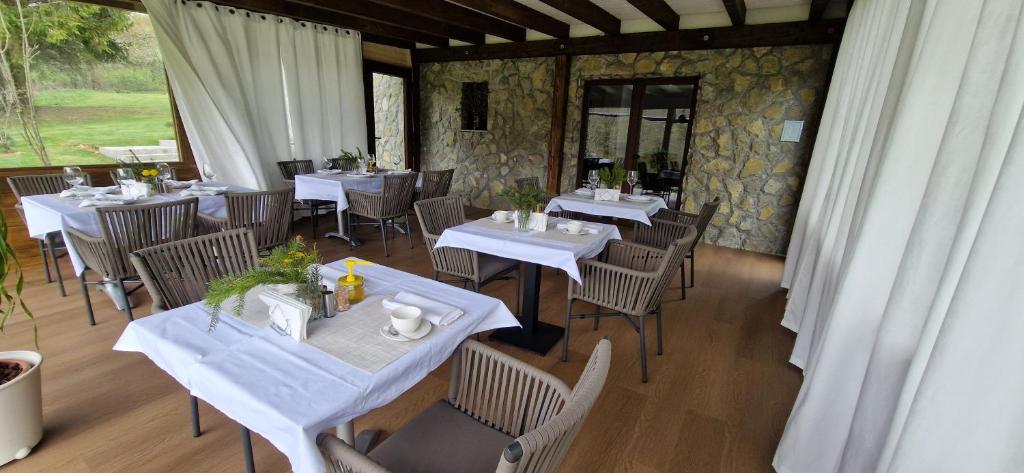 Plitvice Inn في جيزيرسي: غرفة طعام مع طاولات وكراسي بيضاء