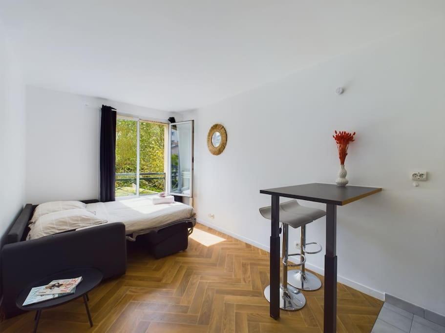 een kamer met een bed, een tafel en een raam bij Cozy Studio vue Parc in Rueil-Malmaison