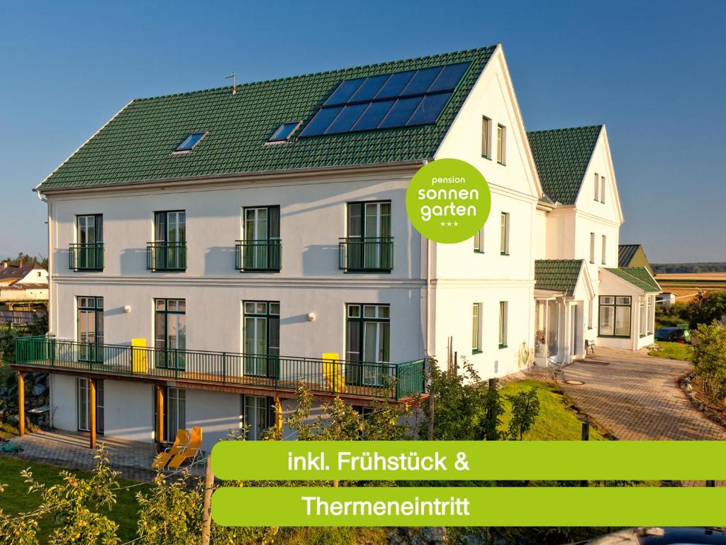 uma casa branca com painéis solares no telhado em Pension Sonnengarten & Therme included - auch am An- & Abreisetag! em Lutzmannsburg