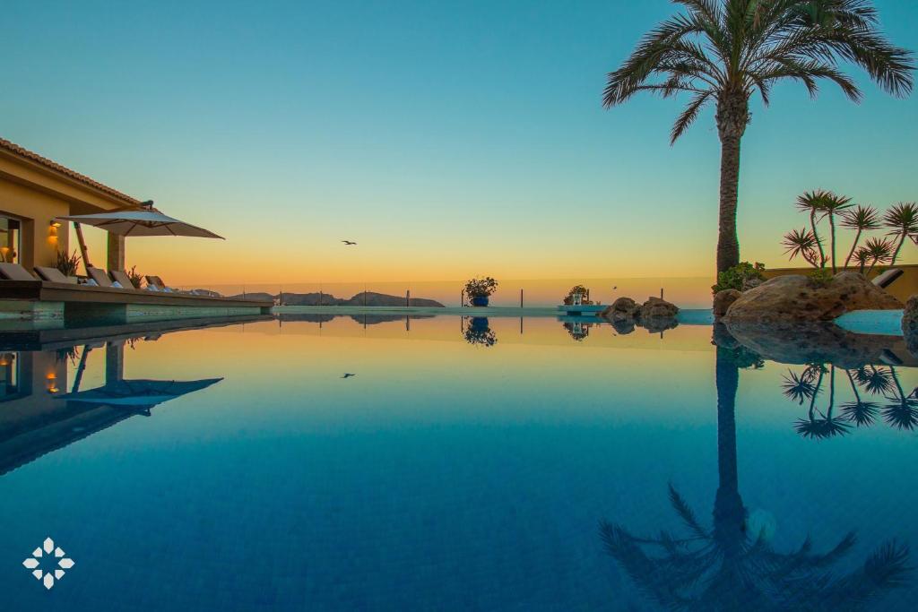 una piscina con una palmera y la puesta de sol en Villa Estrella de Moraira by Abahana Luxe en Moraira