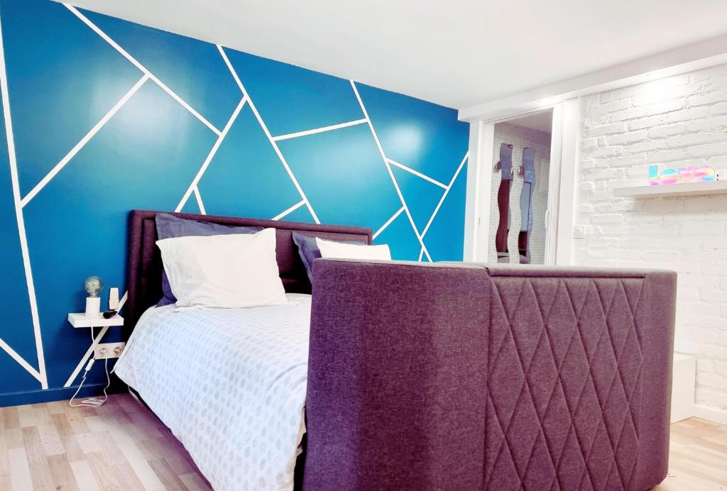 a bedroom with a bed and a blue wall at LA CAMPAGNE à PARIS in Saint-Cloud