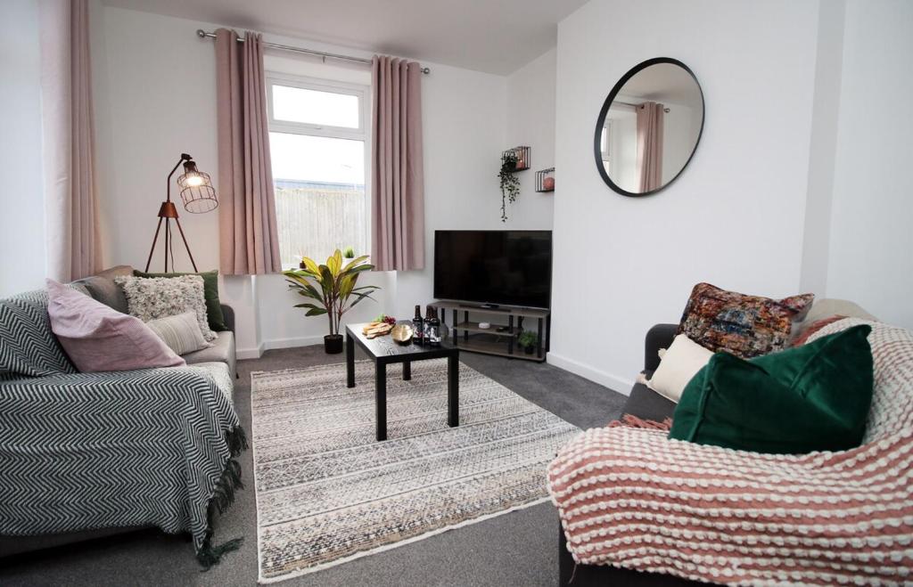ein Wohnzimmer mit 2 Stühlen und einem TV in der Unterkunft Kingsway House by Tŷ SA - Spacious 4bed in Newport in Newport