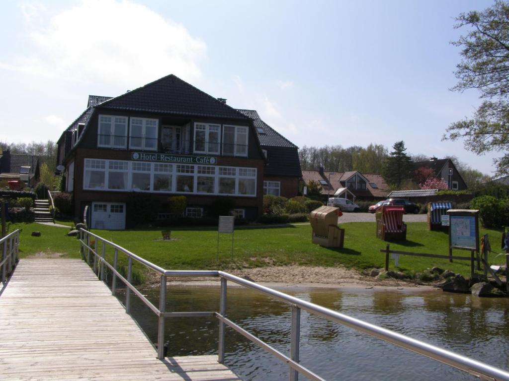 a building with a wooden walkway next to a body of water at Hotel Fährhaus Niederkleveez in Bösdorf