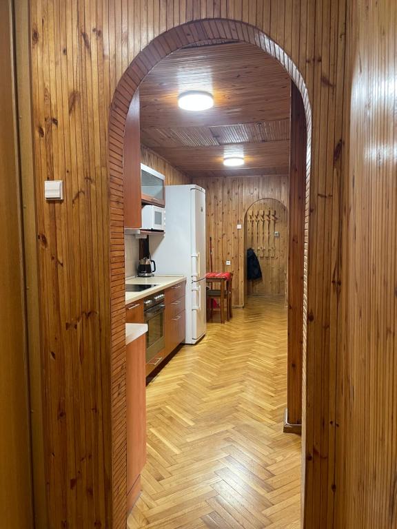 een gewelfde deur naar een keuken met houten wanden bij Cozy two-room apartment in Druskininkai