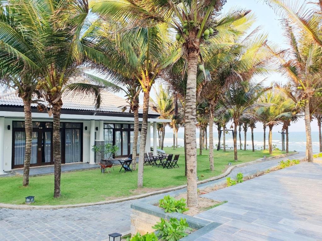 una fila de palmeras frente a un edificio en Starlight Villa Beach Resort & Spa, en Phan Thiet