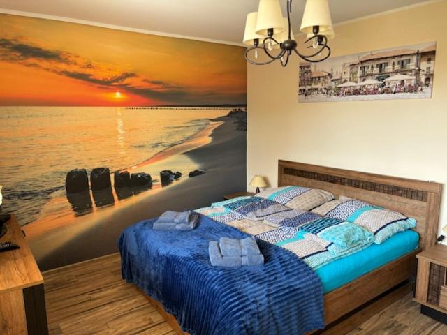 a bedroom with a bed with a painting of a beach at Apartament z Tarasem in Ustka