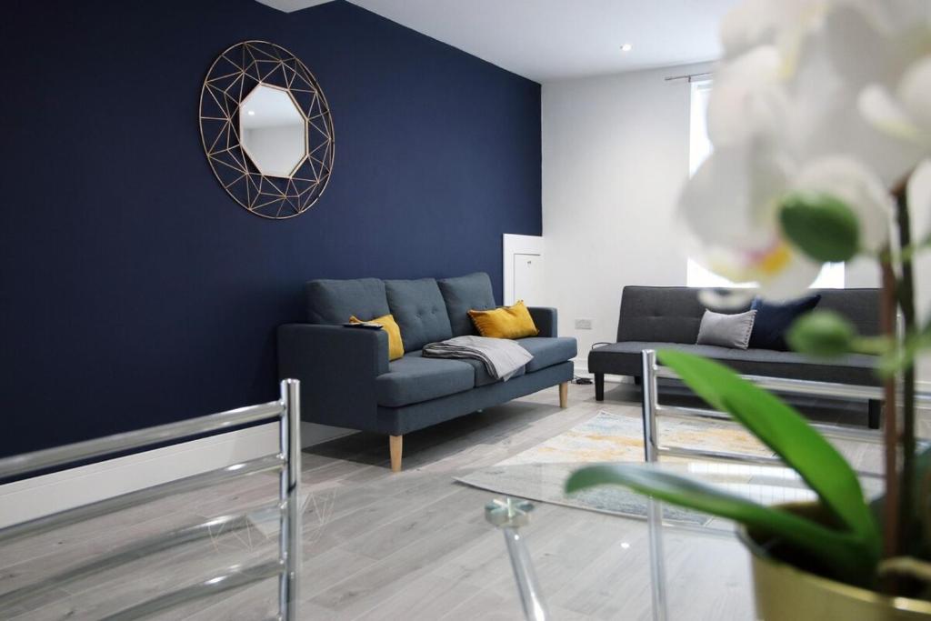 a blue living room with a couch and a mirror at Station Terrace by Tŷ SA - 3 Bed in Mountain Ash in Quakers Yard