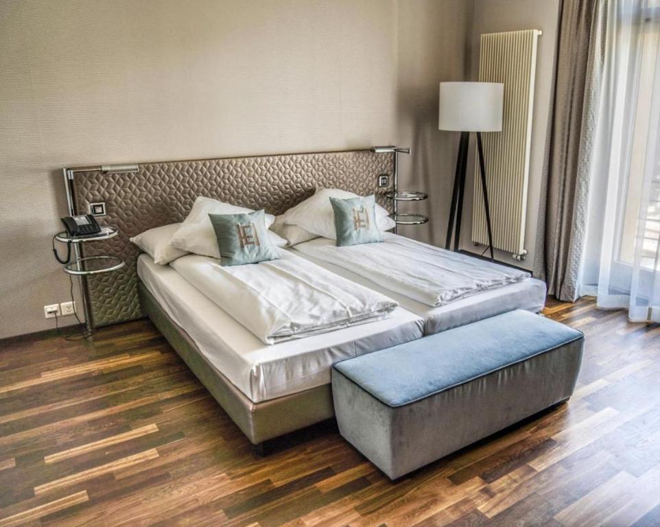 a bedroom with a large bed and a ottoman at Art Déco Hotel Elite in Biel