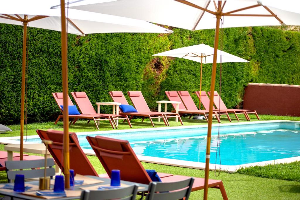 un grupo de sillas y sombrillas junto a una piscina en Hôtel La Perna, en Pernes-les-Fontaines