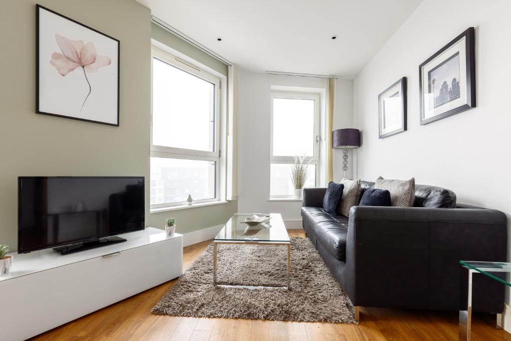 uma sala de estar com um sofá preto e uma televisão de ecrã plano em The Islington Collection em Londres