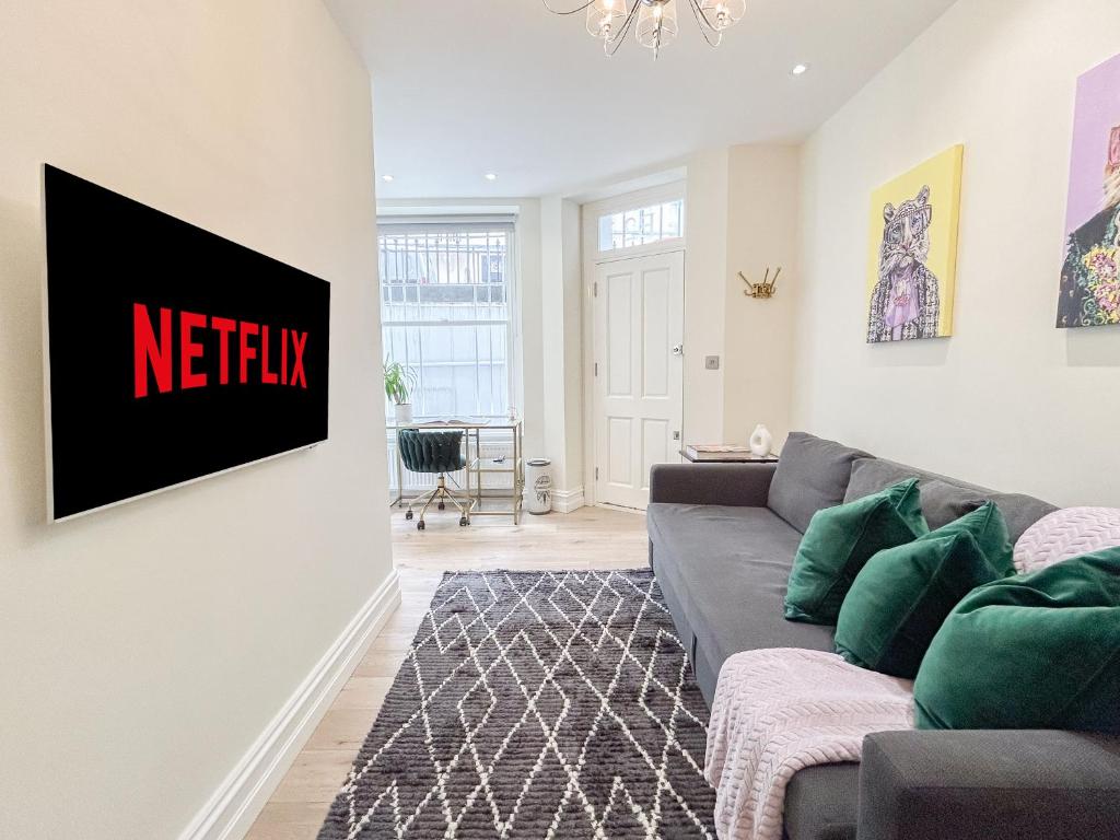 uma sala de estar com um sofá e uma placa de netflix na parede em Urban getaway in the heart of South Kensington em Londres