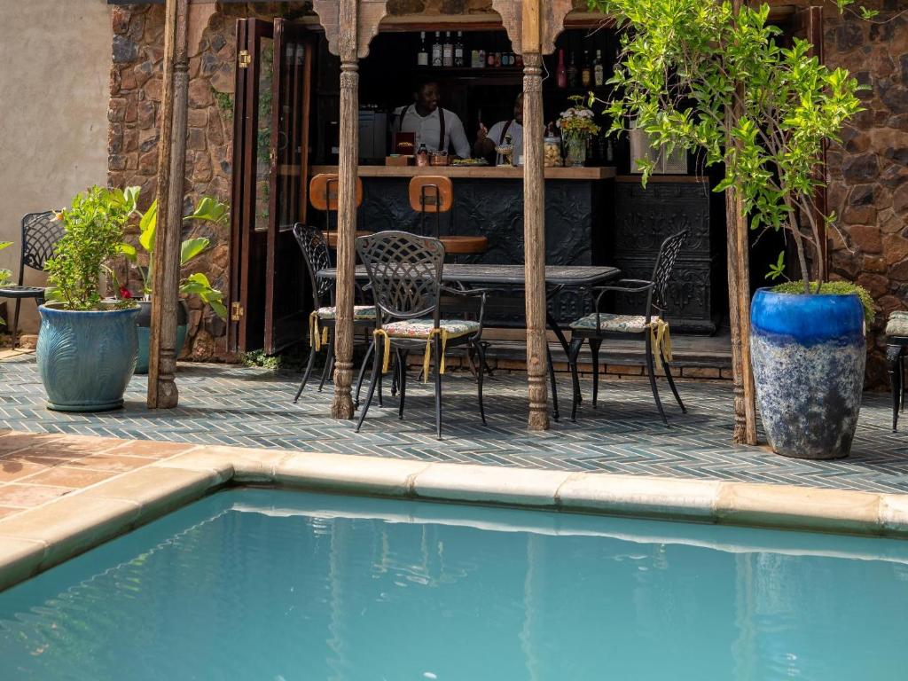 a swimming pool with chairs and a table and a restaurant at Bella Bohemia Spa, Venue and Guest Farm in Roodeplaat