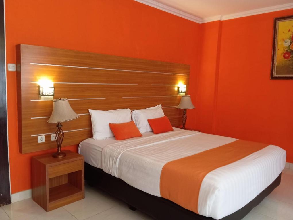 - une chambre avec un grand lit aux murs orange dans l'établissement Alamsagita Puncak Hotel & Resort, à Ciloto