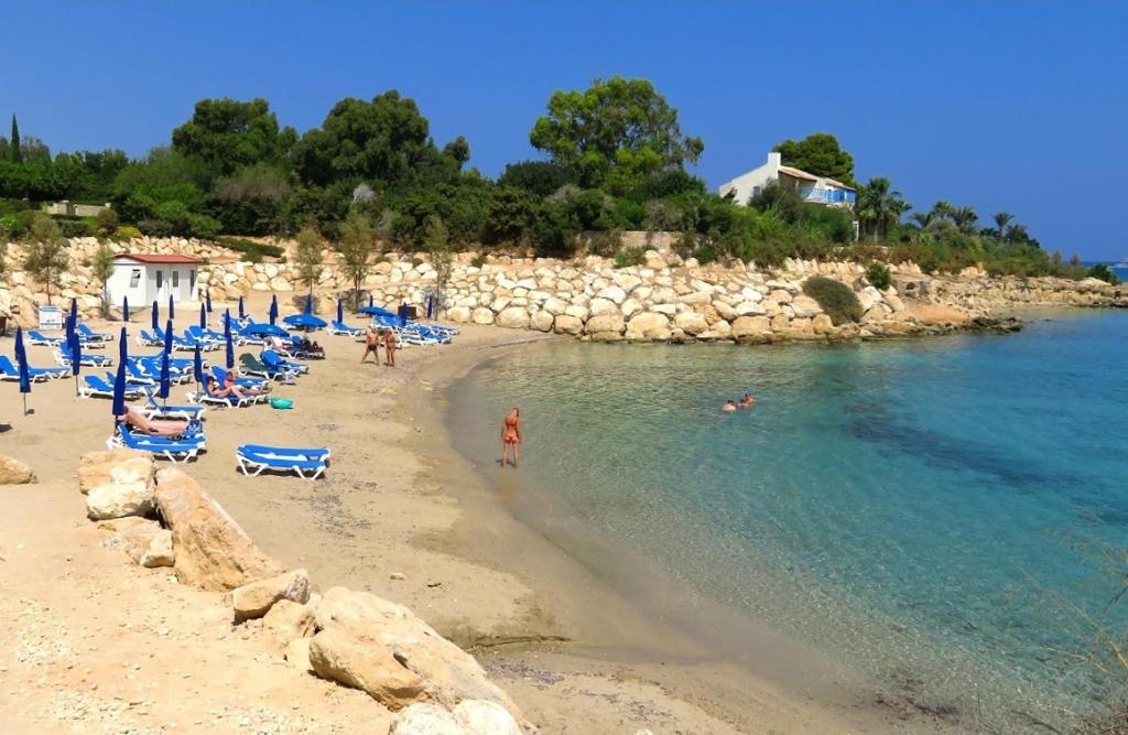 una playa con sillas azules y gente en el agua en Beach House, en Protaras