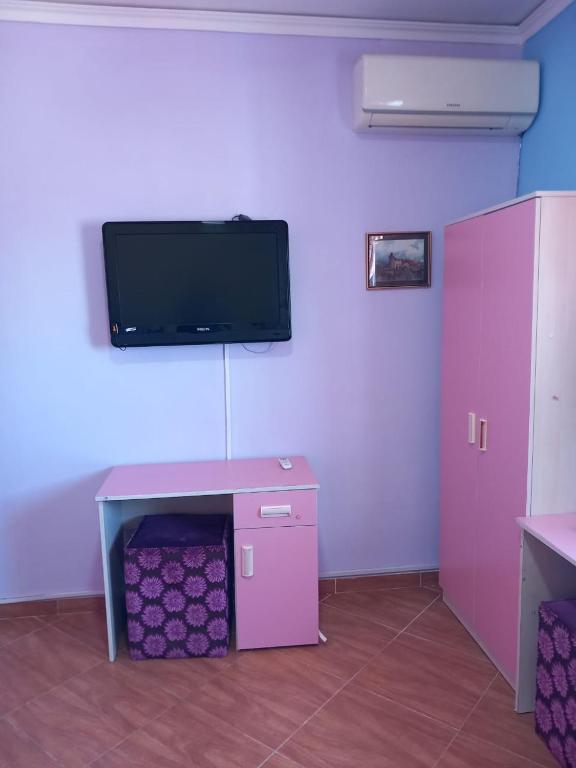 Zimmer mit einem rosa Tisch und einem TV an der Wand in der Unterkunft appartement à larache in Larache