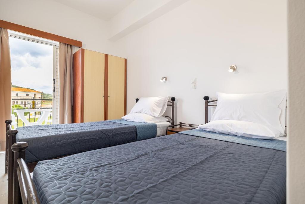 two beds in a room with a window at Valianos Studios in Alikanas
