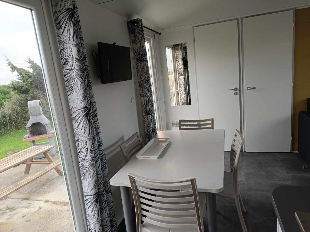 a dining room with a white table and chairs at Mobilhome Indien in Oye-Plage