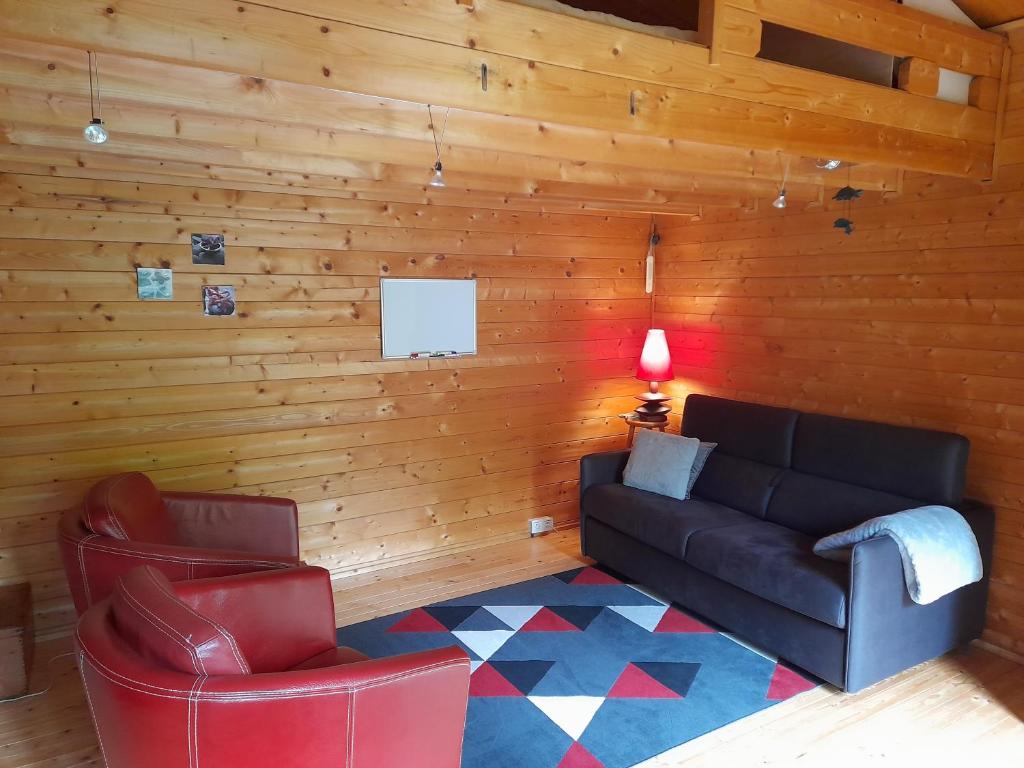 ein Wohnzimmer mit einem Sofa und einem Stuhl in der Unterkunft Chalet indépendant proche centre ville in Le Mans
