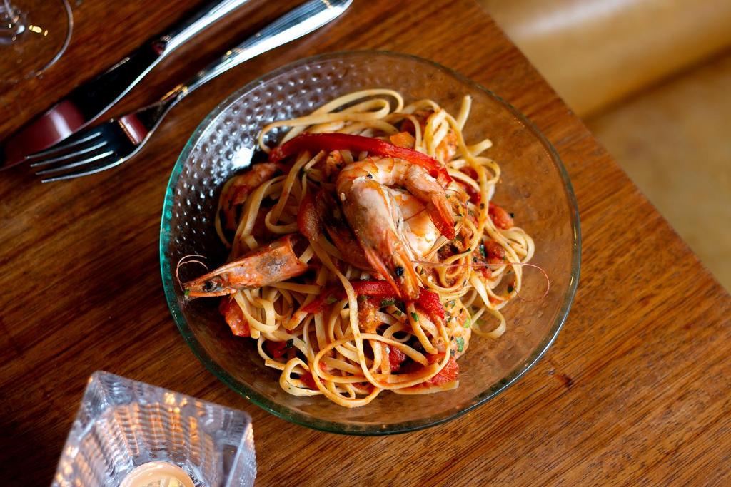 a bowl of food with shrimp and noodles on a table at St Giles London – A St Giles Hotel in London