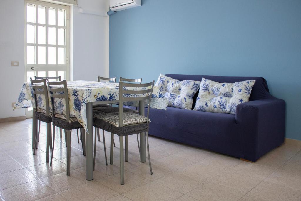 ein blaues Sofa mit einem Tisch und Stühlen in einem Zimmer in der Unterkunft Casa Rosa sul Mare in Capo dʼOrlando