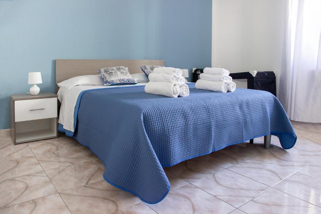 een blauw bed met handdoeken erop bij Casa Rosa sul Mare in Capo dʼOrlando