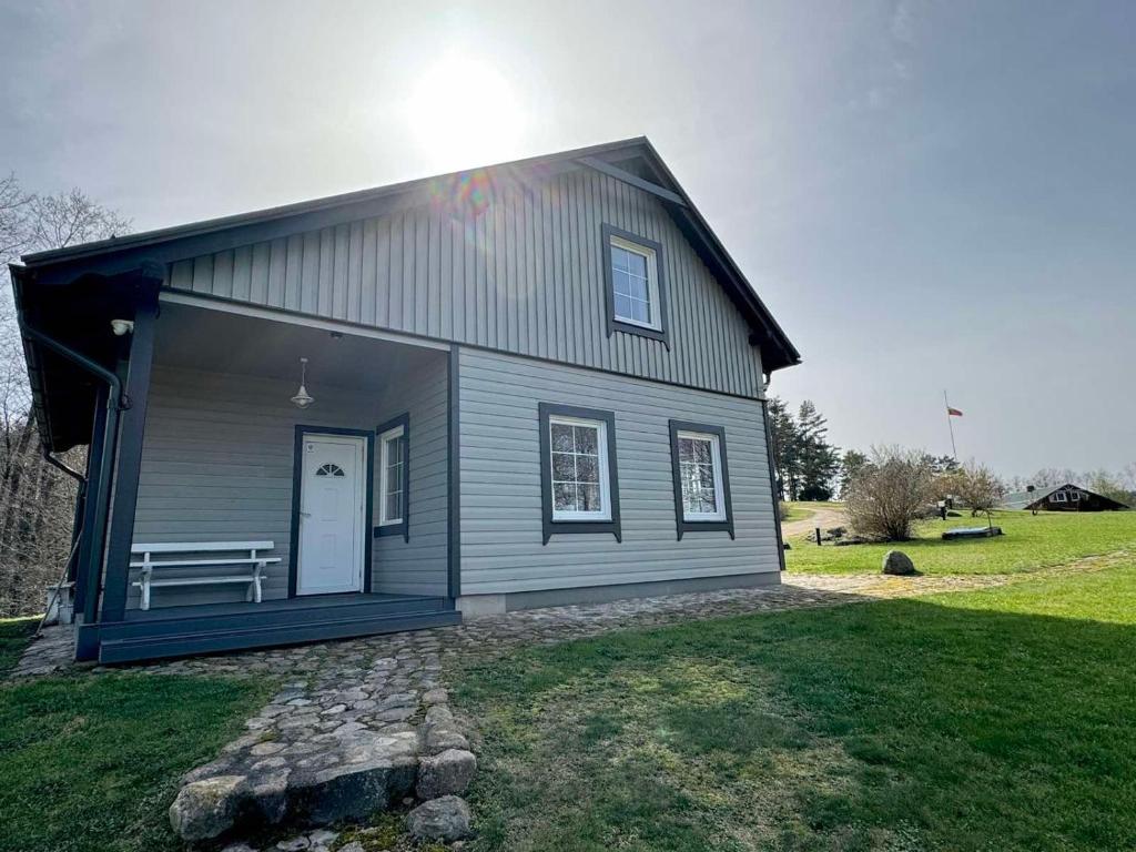 a gray house with a bench on the side of it at Two lakes villas&camps in Markutiškės
