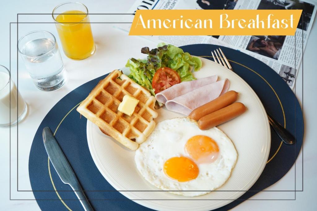 a plate of breakfast food with eggs sausage and waffles at One Deves in Bangkok