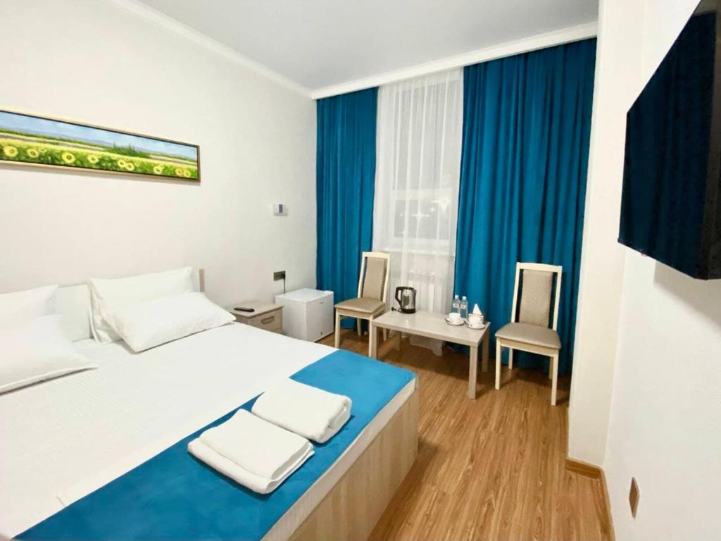 a bedroom with a large bed and blue curtains at QUL-Khadisha in Astana