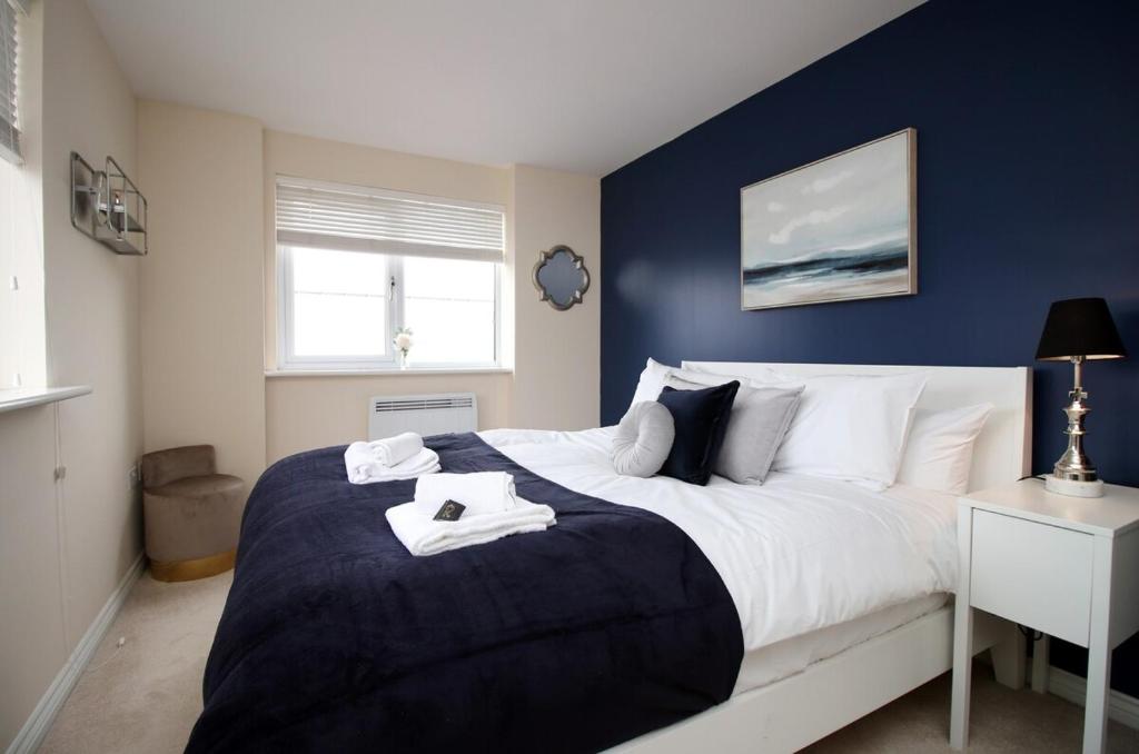 a bedroom with a large bed with a blue wall at Upper Millennium by Tŷ SA - Free Parking in Newport