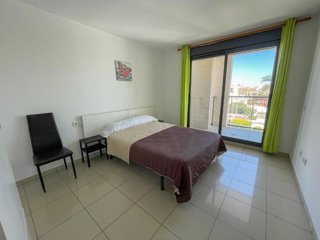 a bedroom with a bed and a chair and a window at Apartamentos Playa de Benicarló 3000 in Benicarló