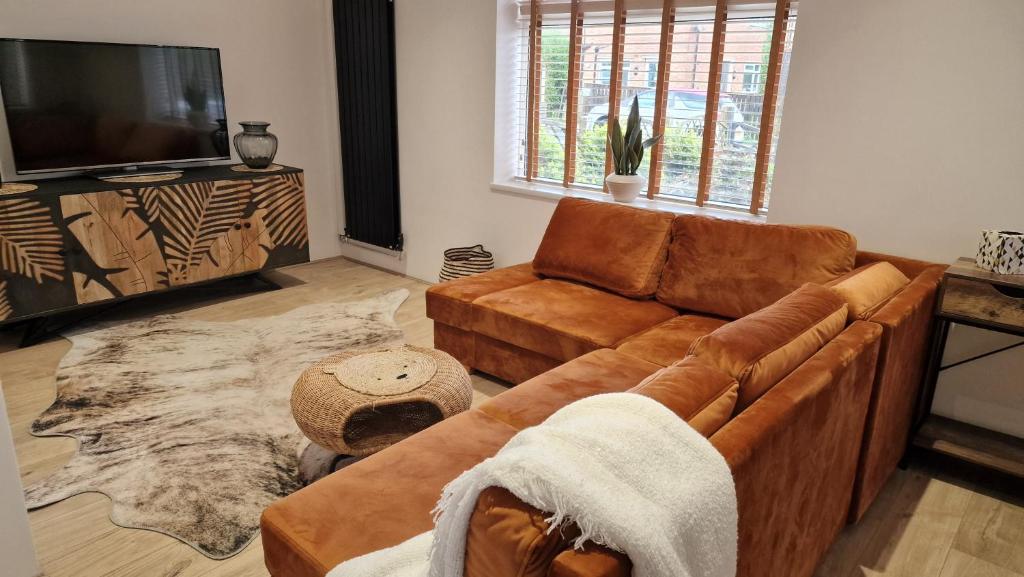 a living room with a brown couch and a television at Designed Gem in Cayton