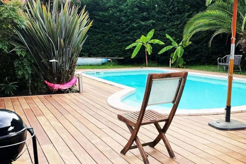 una terrazza in legno con sedia accanto alla piscina di Villa élégante à La Teste-de-Buch avec piscine privée a La Teste-de-Buch