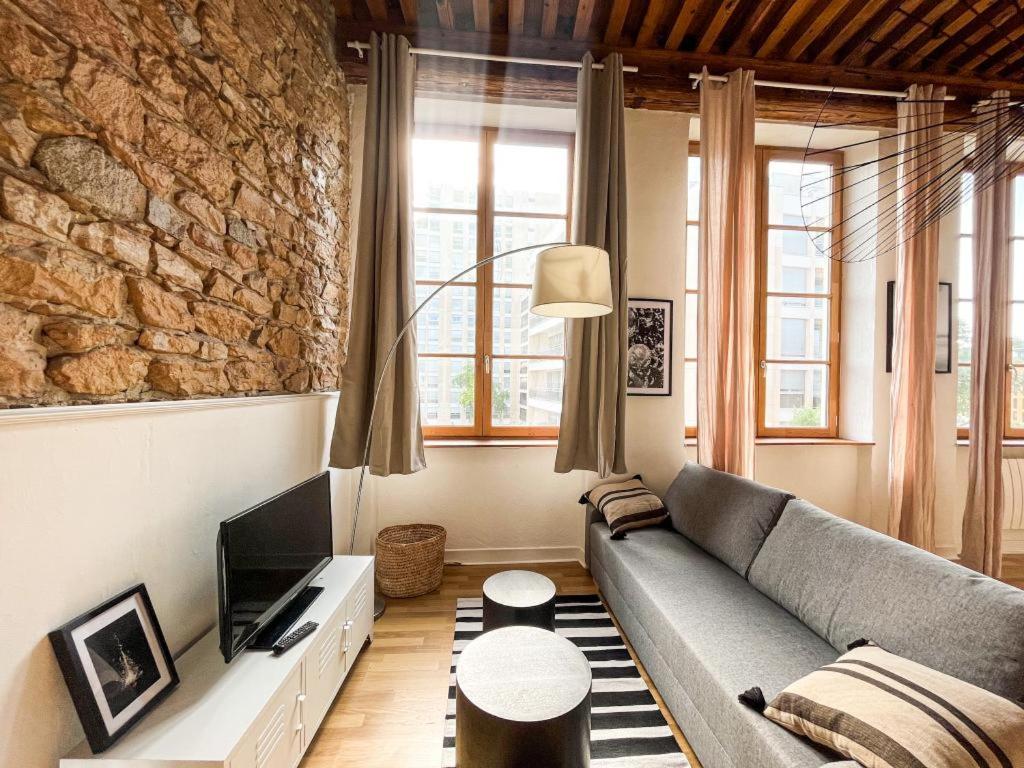 - un salon avec un canapé et un mur en pierre dans l'établissement Suite Cartier, à Lyon