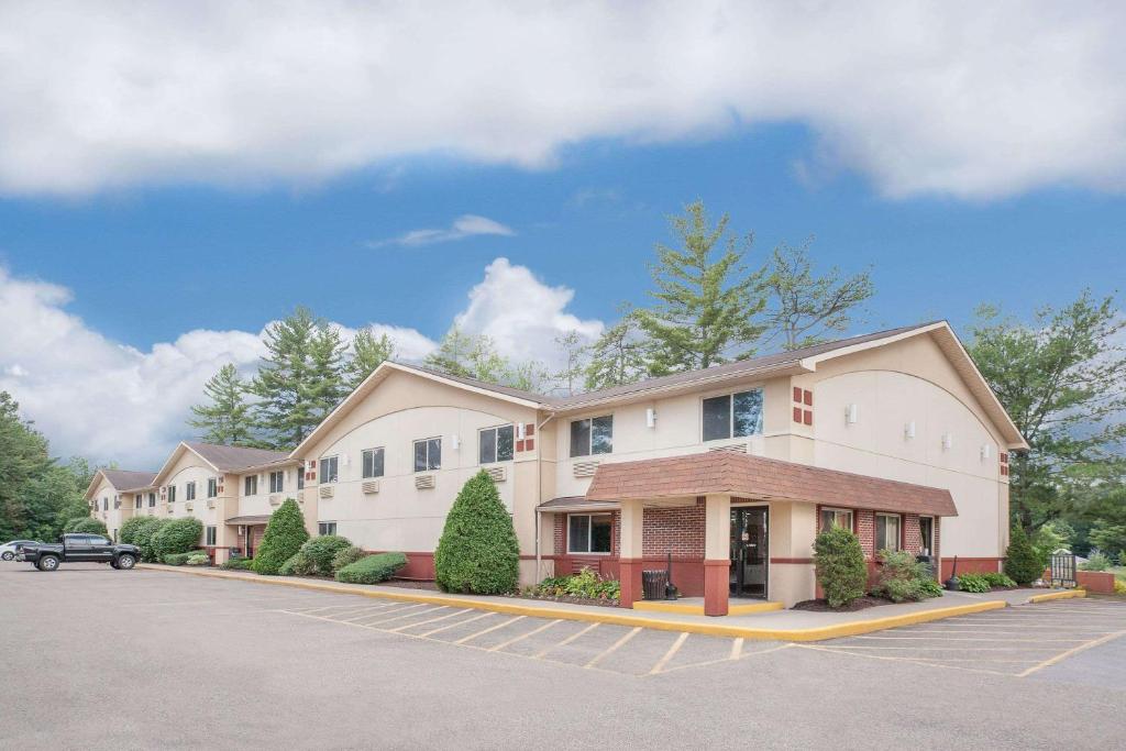 a building with a car parked in a parking lot at Super 8 by Wyndham Queensbury Glens Falls in Queensbury