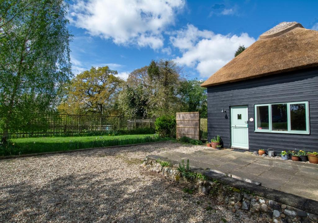 a cottage with a thatched roof and a driveway at Little Barn in Upton