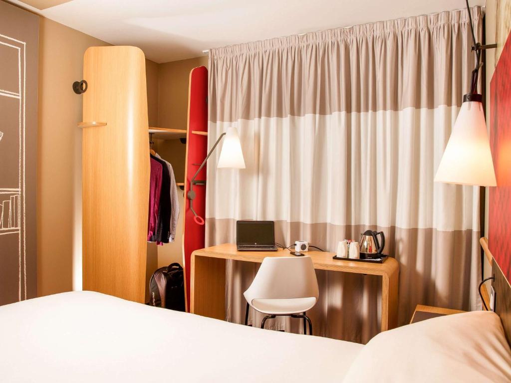 a bedroom with a bed and a desk with a laptop at ibis London City - Shoreditch in London