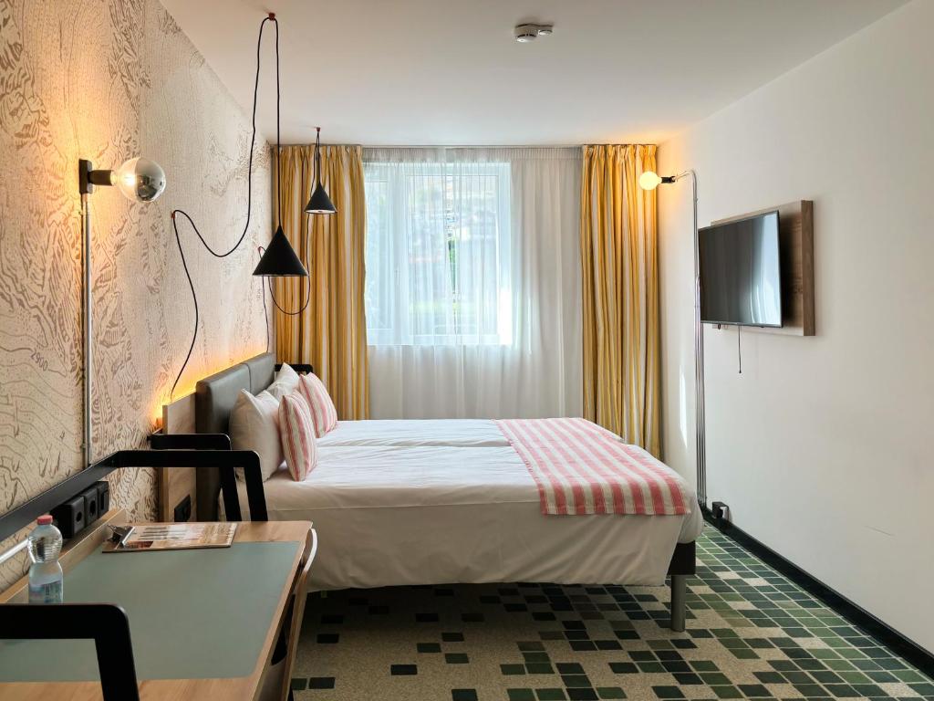 a hotel room with a bed and a desk at Nonanteneuf Appart-hôtel - Sierre in Sierre