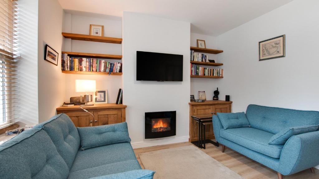a living room with two blue chairs and a fireplace at Ryecroft Cottage - Matlock in Two Dales