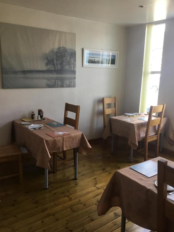 a dining room with two tables and chairs and a painting at Dene House in Great Yarmouth